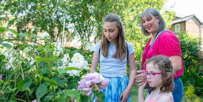 A mother and her two young daughters looking at flowers