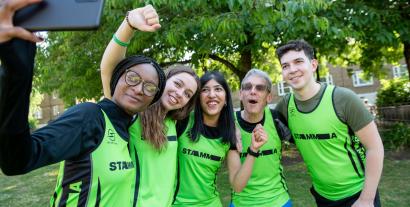 Three women and two men in running outfits posing for a selfie photograph taken by one of the women