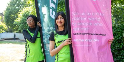 Two women in running outfits holding flags and looking at the camera