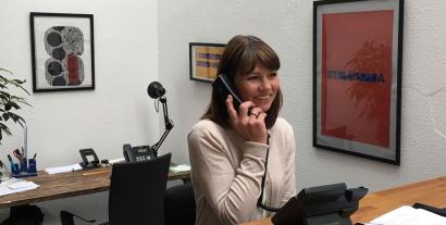 A woman at a desk speaking into a phone