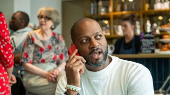 A man in a coffee shop talking into a mobile phone