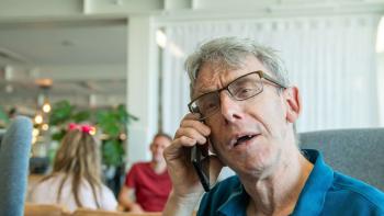 A man sitting in an armchair speaking into a mobile phone