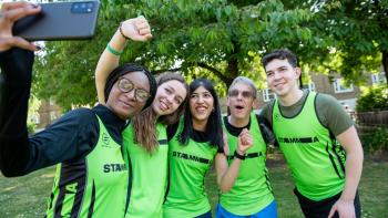Three women and two men in running outfits posing for a selfie photograph taken by one of the women