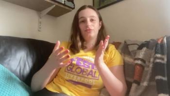 A woman sitting on a sofa gesticulating with her hands and looking at the camera