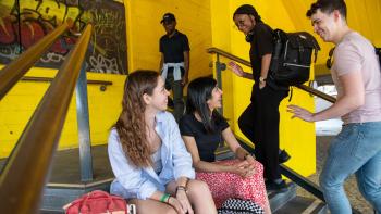 Two women sitting on steps looking at a man and a woman who are walking up the steps
