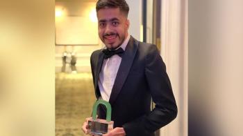 A man holding an award and looking at the camera, smiling