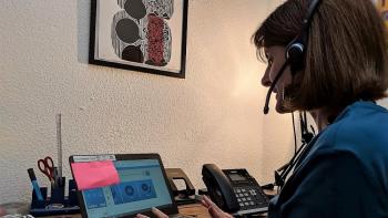 A woman sitting in front of a laptop computer and wearing a headset
