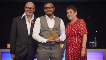 A man posing with an award beside two other people