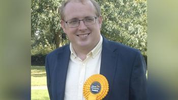 A man wearing a parliamentary rosette