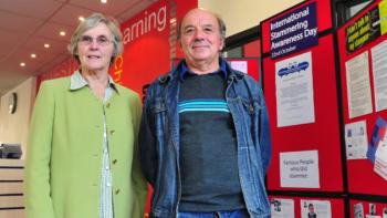 A man and woman standing next to information boards, smiling for the camera