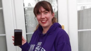 A young woman holding up a smartphone and smiling