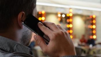 The back of a man's head as he speaks into a mobile phone. 