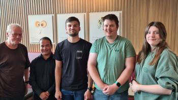 Four men and one woman standing in a line and smiling