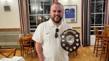 A man holding a trophy, smiling for the camera