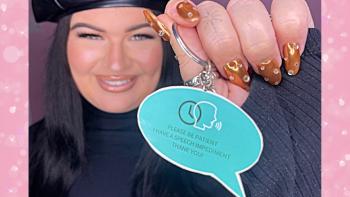A young woman smiling and holding up a speech bubble-shaped keyring with 'Please be patient, I have a speech impediment. Thank you!'