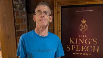 A man smiling in front of a poster with the words 'The King's Speech'