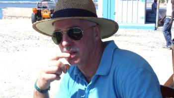 A man on a beach wearing a straw hat and sunglasses