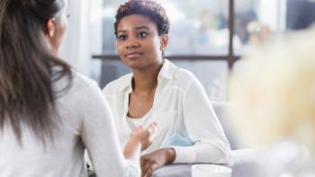 A woman in a therapy setting, talking to another woman, whose face we cannot see
