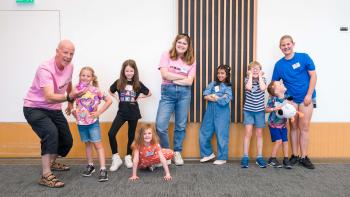 A group of children smiling, with two grown ups 