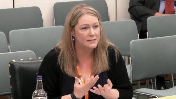 A woman sitting in a meeting room, gesticulating with her hands