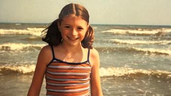 A girl on beach with waves behind her