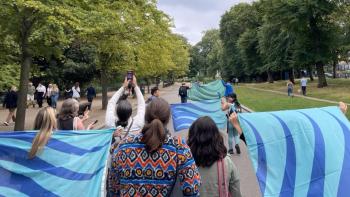 A group of people marching through a park holding flags
