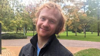 A man in a park looking at the camera and smiling
