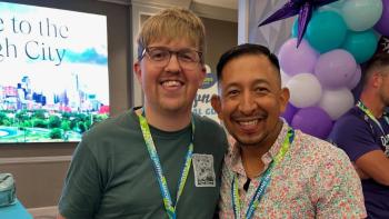 Two men wearing lanyards standing together and smiling