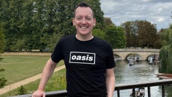 A man standing on a bridge over a river, smiling