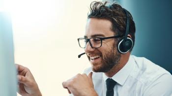 A man in a call centre wearing a phone headset and smiling