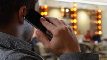 The back of a man's head as he speaks into a mobile phone. 