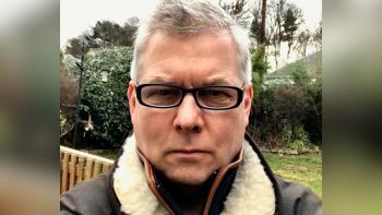 A man wearing glasses in a garden looking at the camera