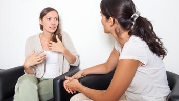 Two women sitting and talking, with one gesticulating with her hands