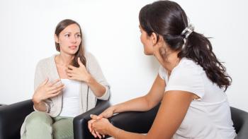 Two women sitting and talking, with one gesticulating with her hands