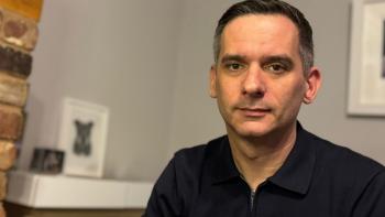 A man looking serious, in front of a living room mantlepiece