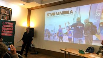 A woman standing in front of a projected screen, presenting to an audience