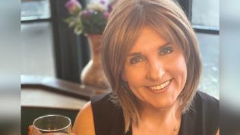 A woman smiling and holding up a glass of wine