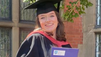 A young woman in a graduating gown, smiling