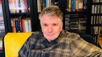 A man sitting in front of a bookshelf and smiling
