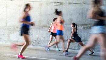 Women running in an urban setting, with one doing stretches