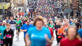 A huge crowd of people running through a street as part of a sponsored run