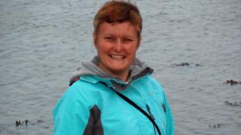 A woman smiling, with a lake behind her