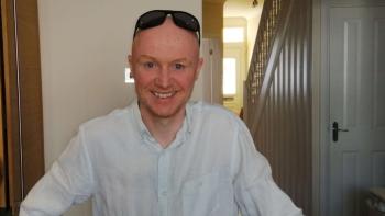 A man smiling, with sunglasses on the top of his head