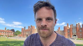 A man smiling, with Hampton Court Palace in the background