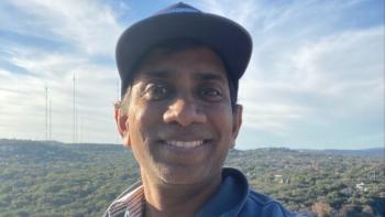 A man smiling, with a backdrop of trees and a horizon
