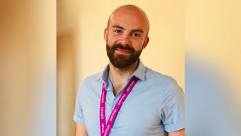 A man wearing a lanyard and smiling