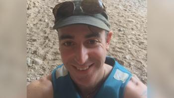 A man standing in sand, smiling