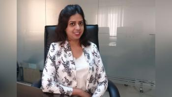 A woman siting in an office looking at the camera and smiling
