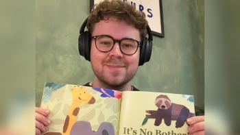 A man wearing headphones and holding up a children's book