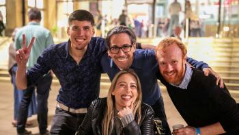 Three men and a woman huddled together and smiling